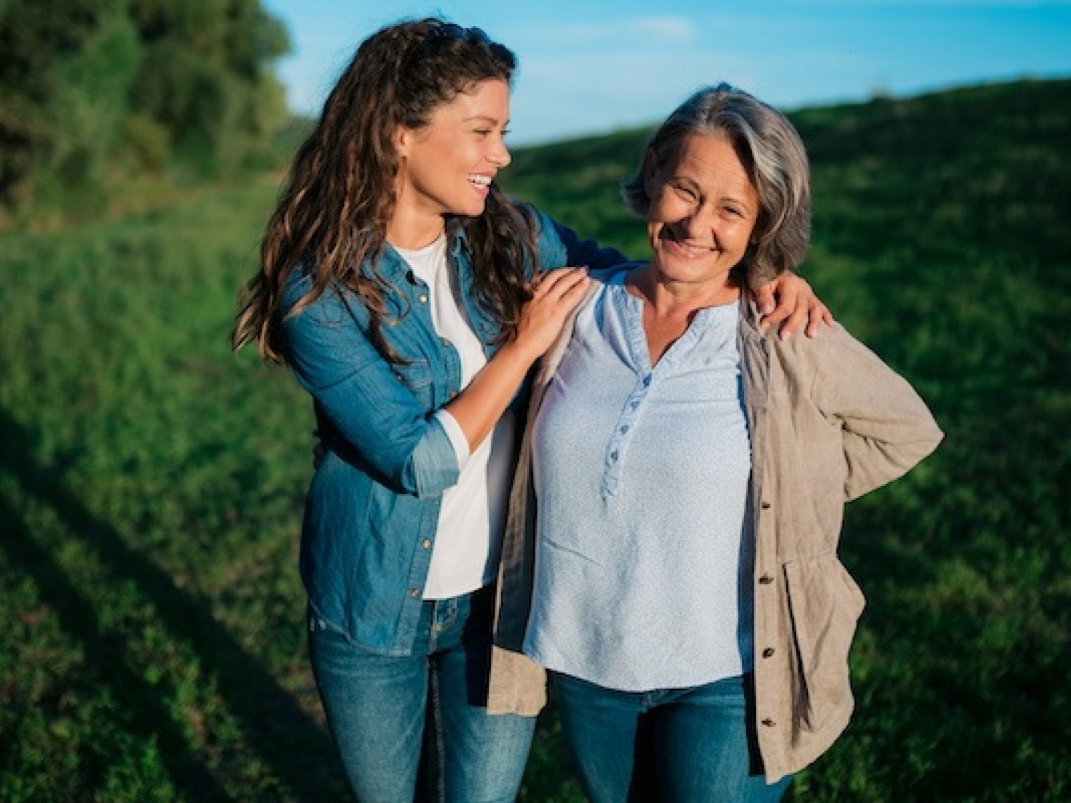 Happy mother and daughter standing outdoors.