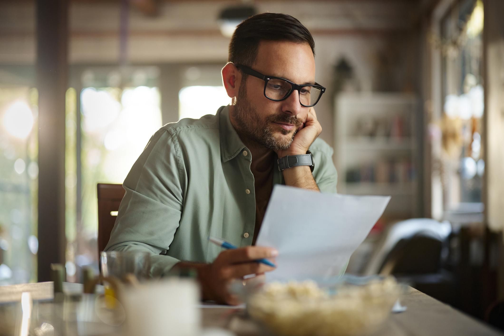 A man sitting at a table looking at his statement of service document.
